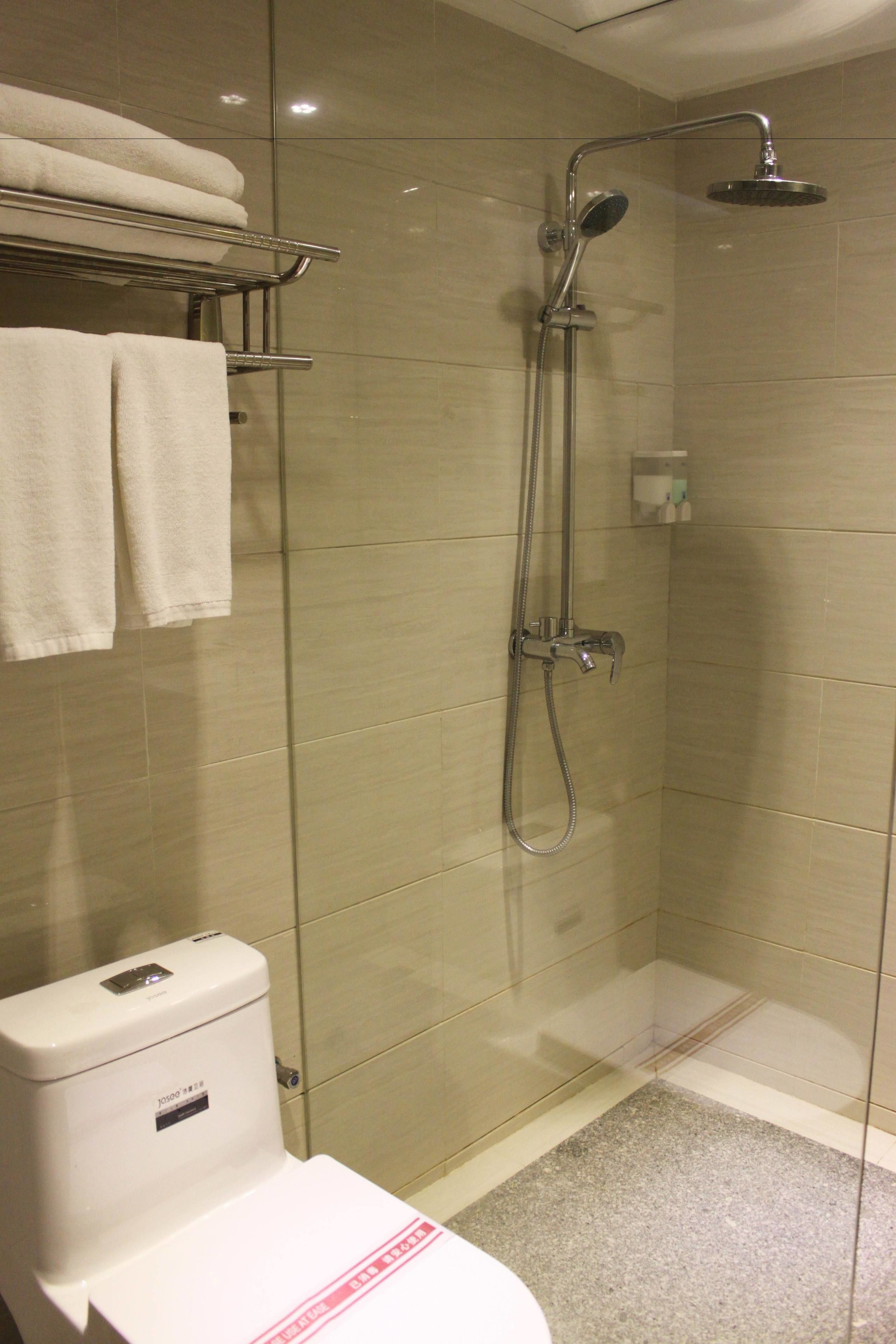 Un baño moderno con cabina de ducha de vidrio, inodoro con panel de control y toallero con toallas dobladas.