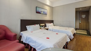 A hotel room with two beds, a red armchair, a painting on the wall, and a wooden floor. - Huangpu Hotel (Guangzhou)