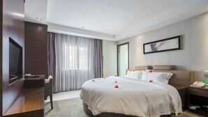 A hotel room with a large bed, a desk, a chair, a TV, and a framed picture on the wall. - Huangpu Hotel (Guangzhou)
