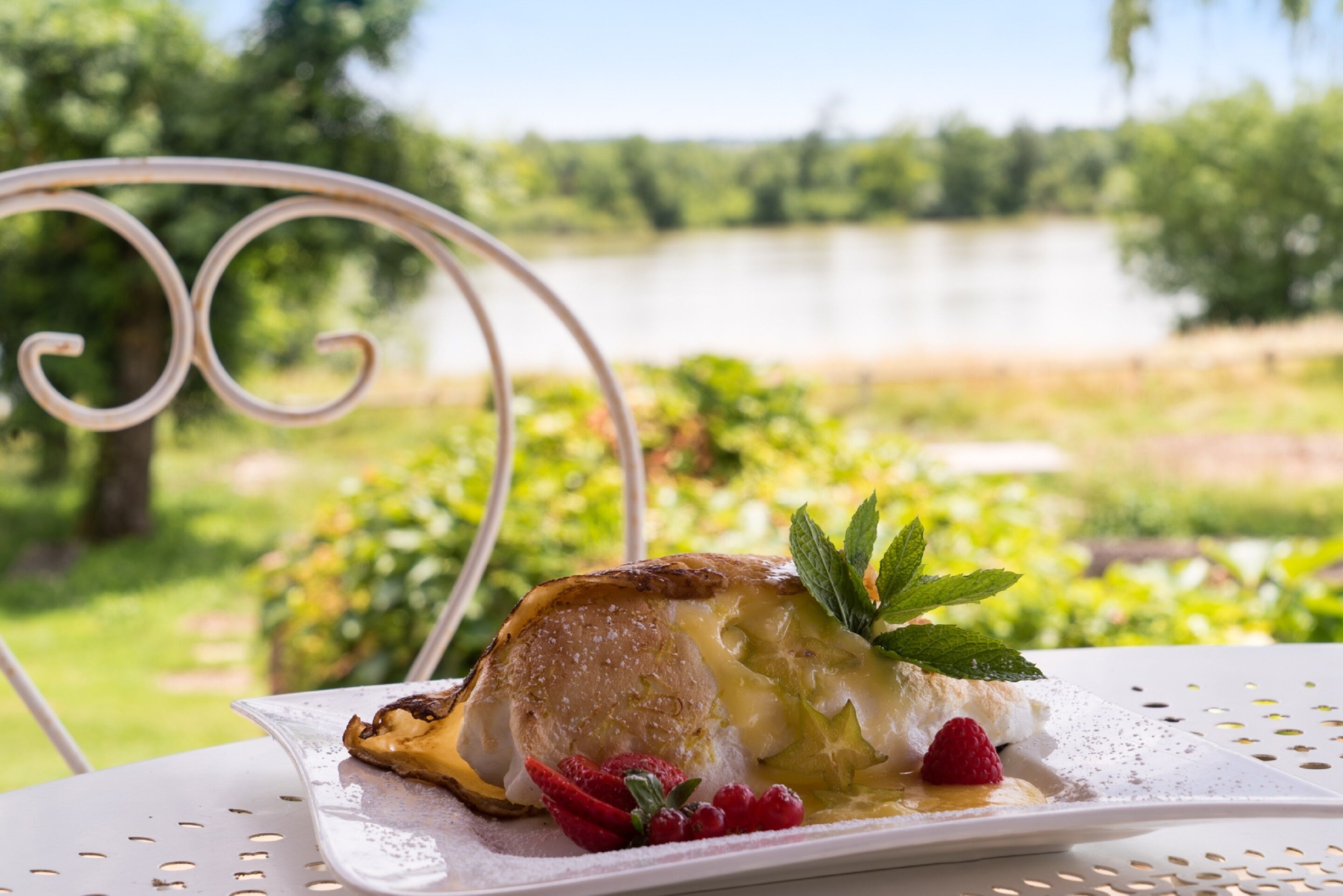 Un postre sobre un plato blanco, con una vista panorámica de un lago al fondo.