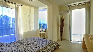 Un dormitorio con cama, ventana, una mesita y un balcón.