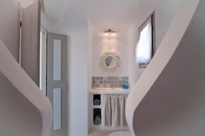 A narrow bathroom with a white sink, a mirror, and a towel rack.