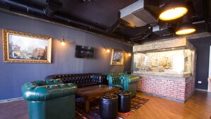 A room with a green leather sectional sofa, a wooden coffee table, and a glass display case with a brick base.