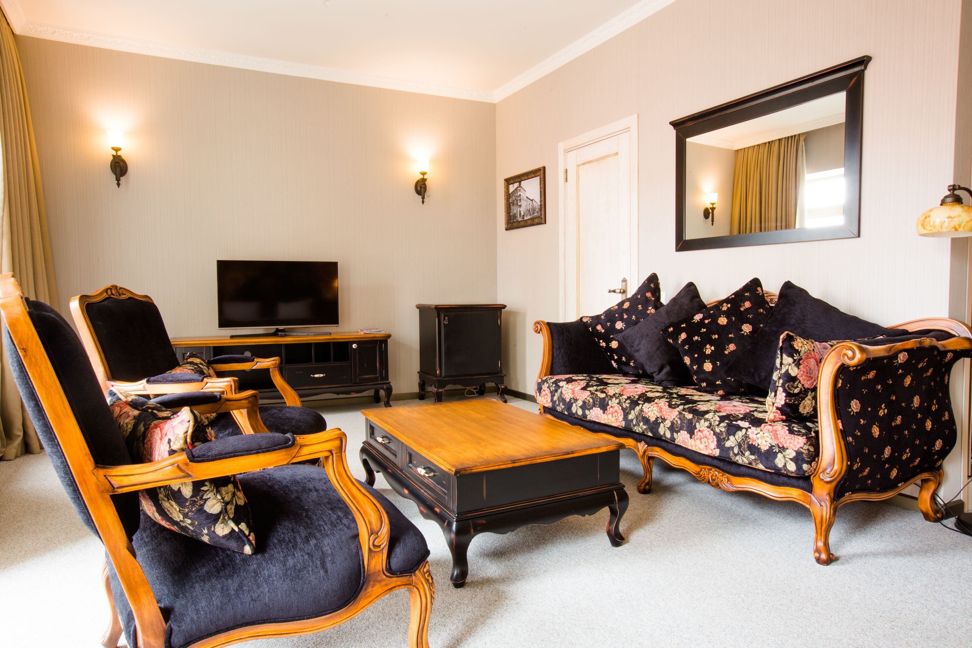 A living room with a sofa, armchairs, a coffee table, a television, and a cabinet.