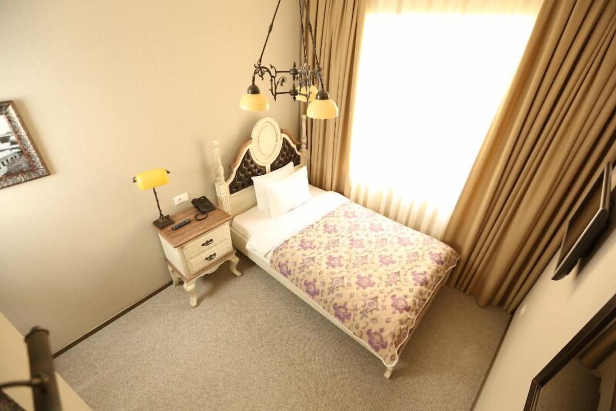 Une chambre à coucher avec un lit, une table de chevet, une lampe et des rideaux.