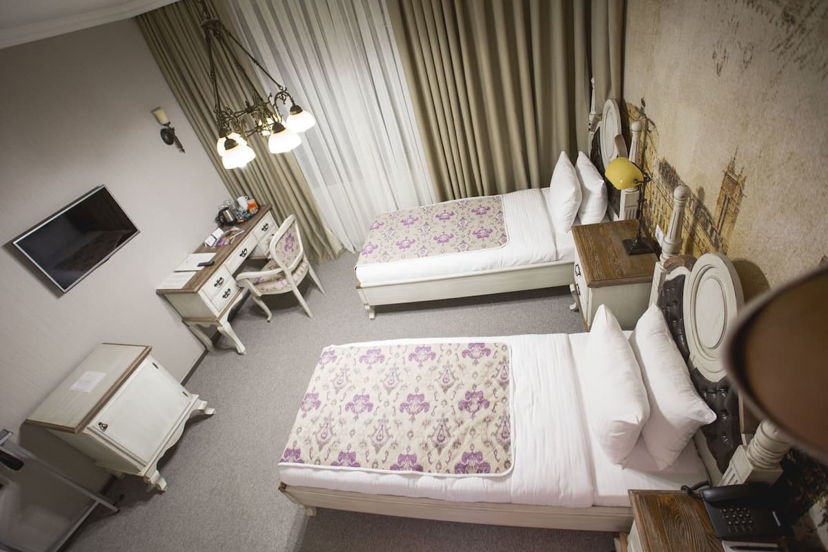Une chambre d’hôtel avec deux lits, un bureau, une chaise, une télévision et un miroir.