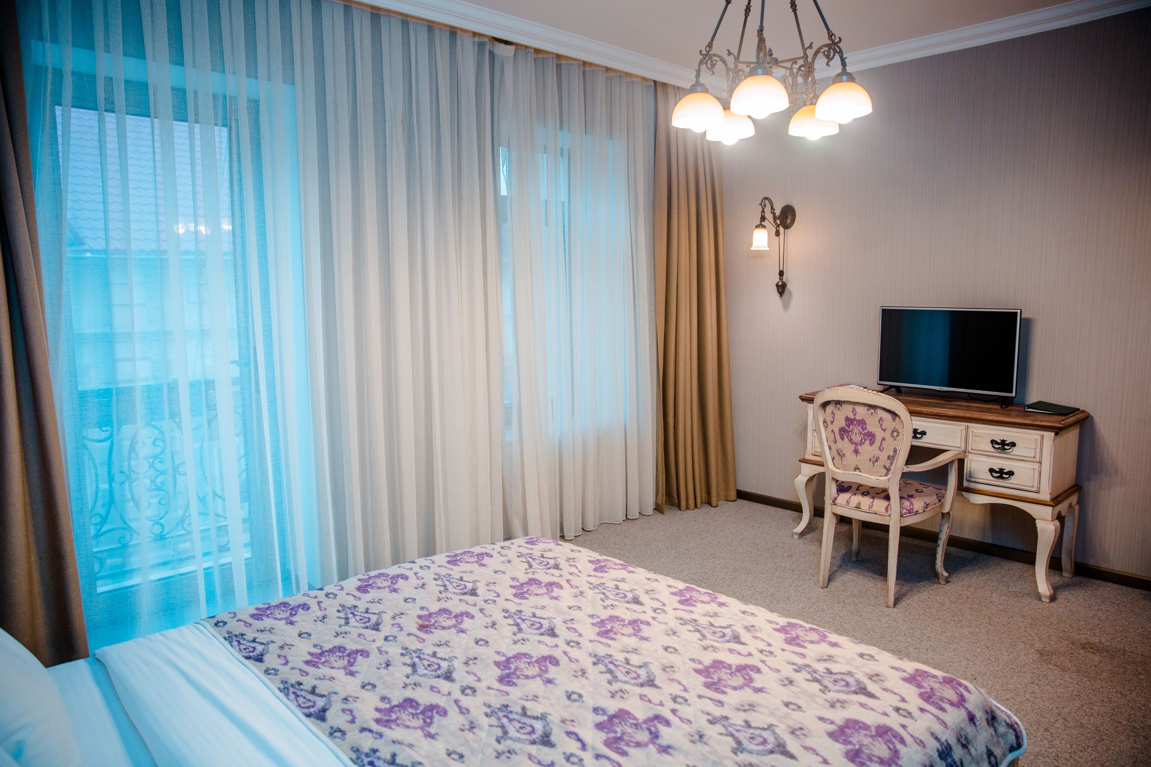 Een hotelkamer met een bed, een bureau met een televisie en gordijnen.