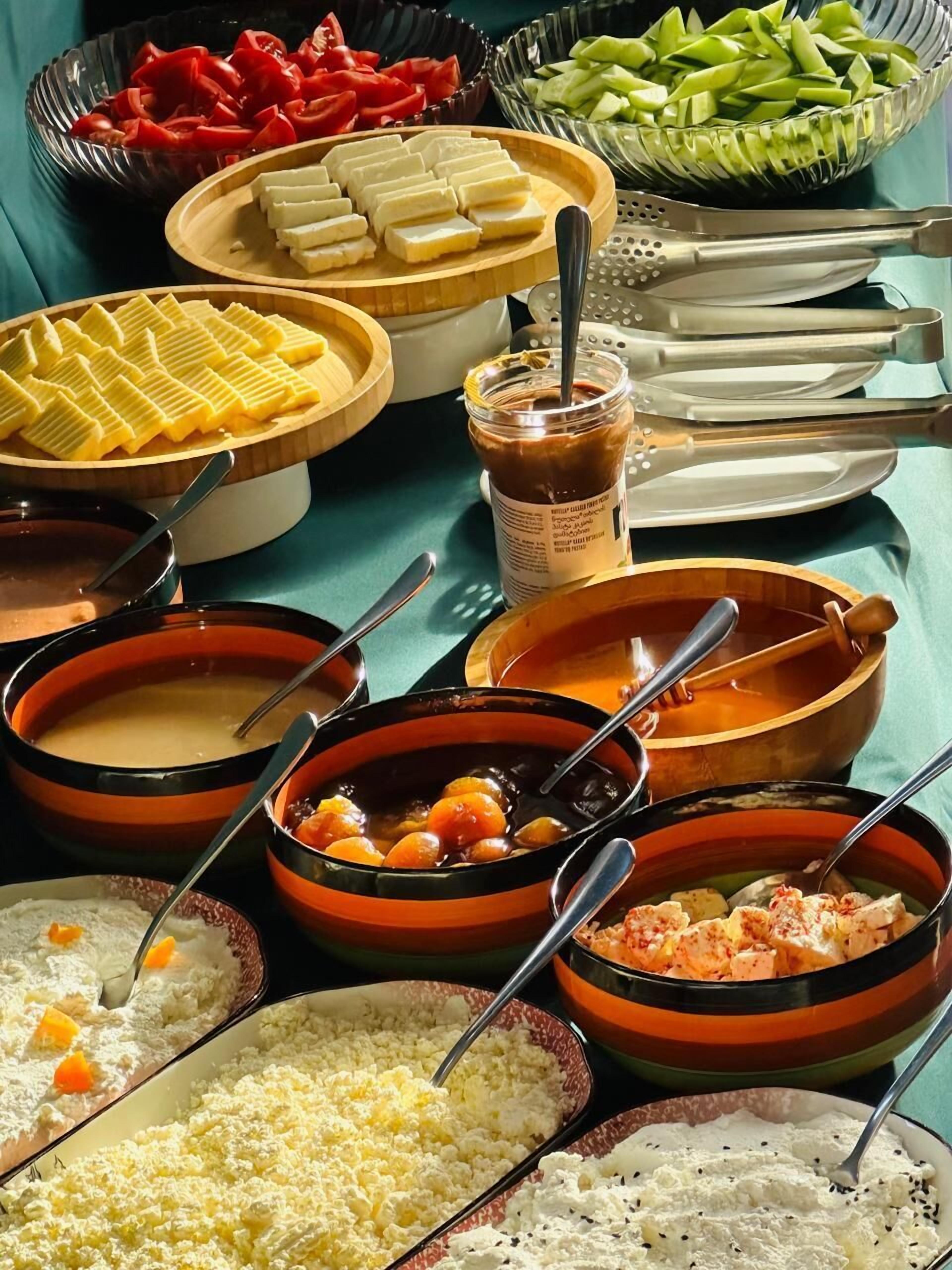 A table with various dishes including soups, a bowl of sliced vegetables, and a jar of sauce.