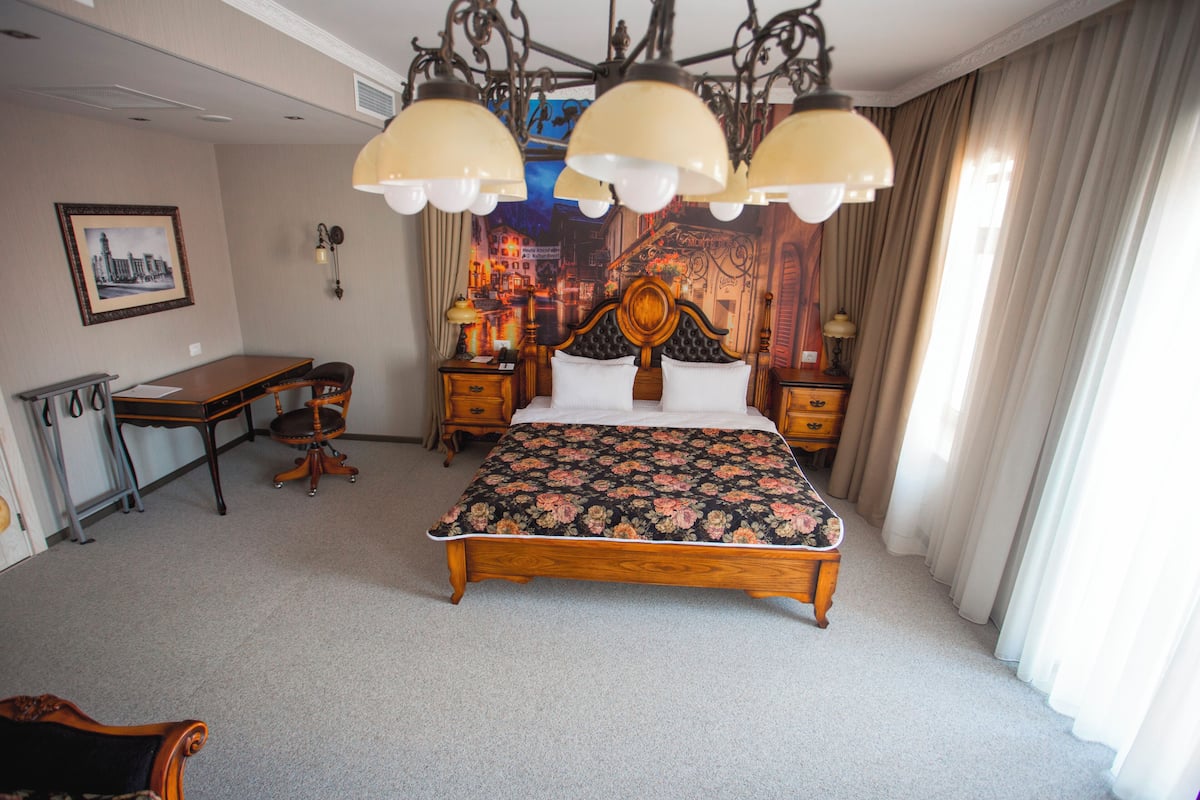 Une chambre d’hôtel avec un grand lit, un bureau, une chaise et un lustre.