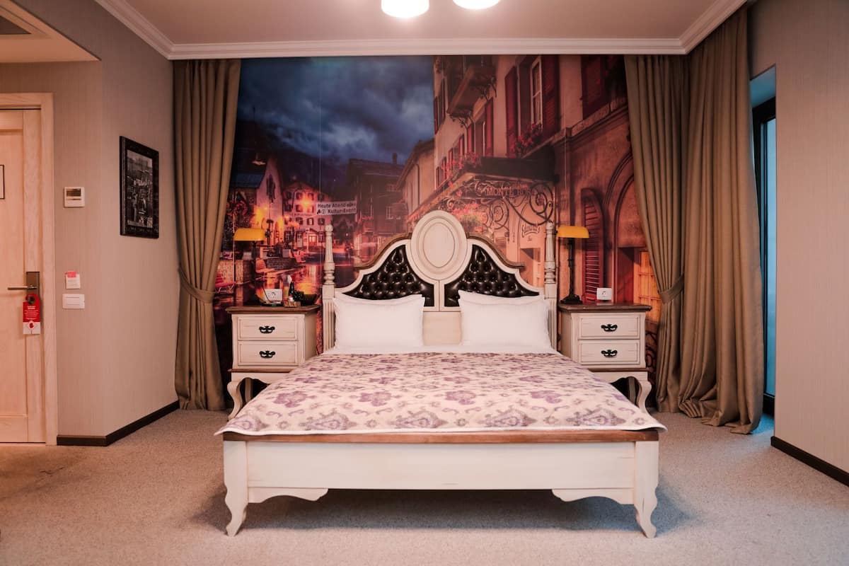 Une chambre à coucher comprenant un lit, des tables de chevet, une tête de lit, une décoration murale et des rideaux.