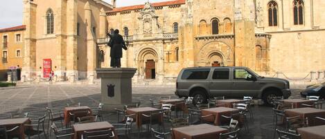 An outdoor café with tables and chairs in front of a historic building with ornate architecture.