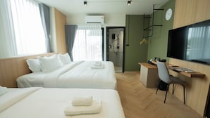 Ett hotellrum med två sängar, ett skrivbord med en stol, en TV och en duschhörna.