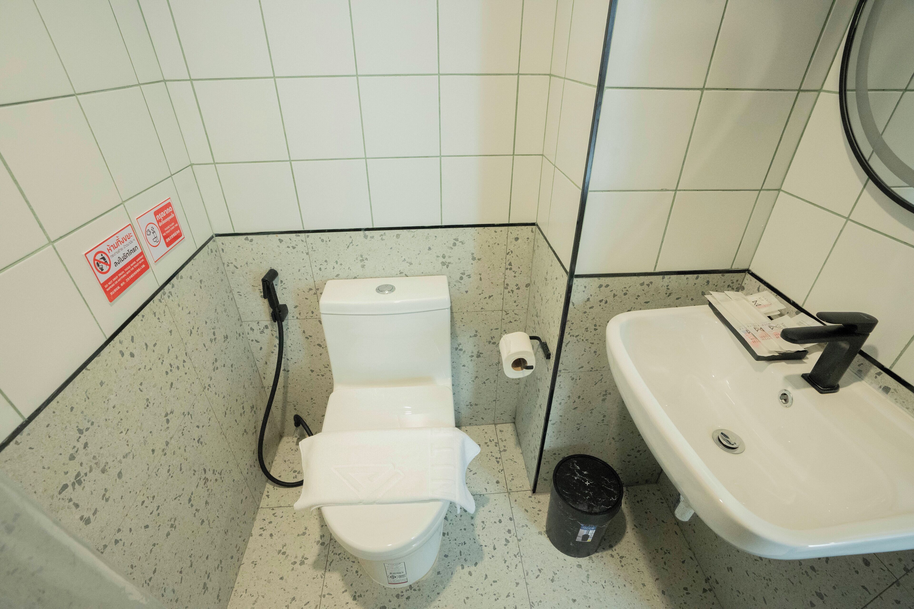 A small bathroom with a toilet, sink, and a trash bin.