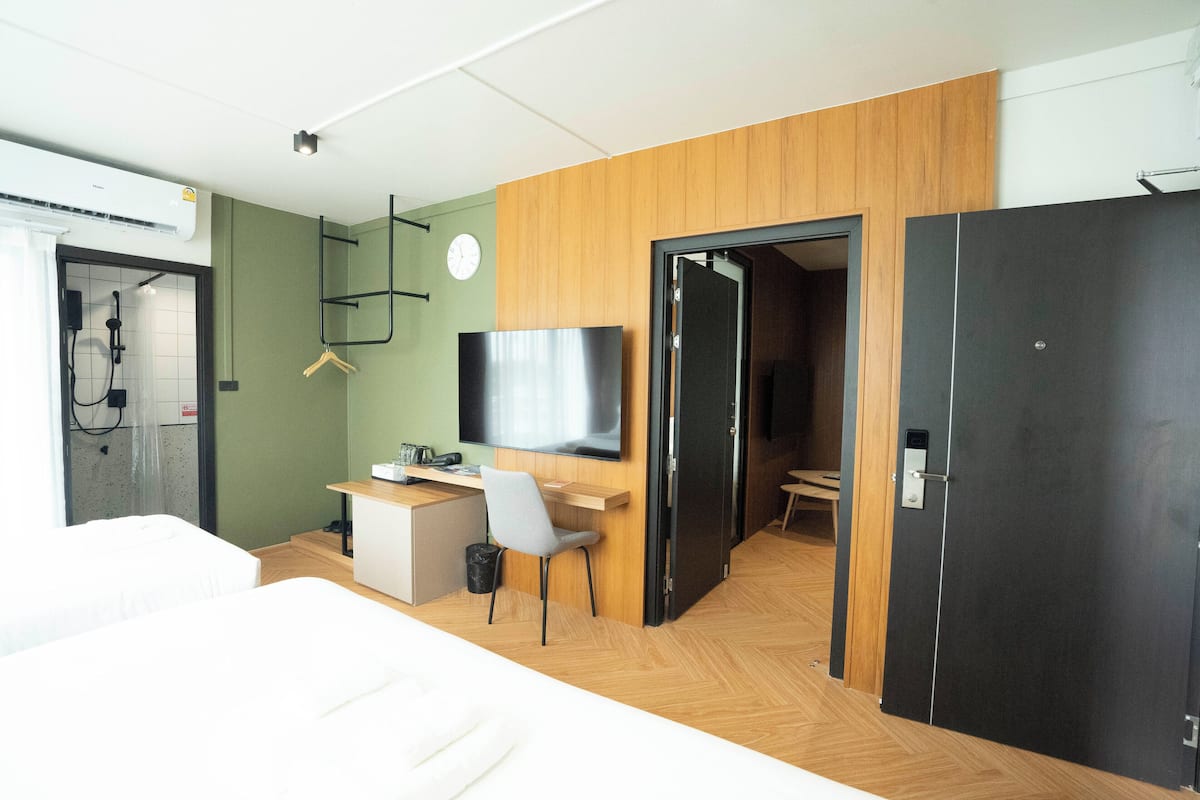 A modern hotel room with a bed, a desk, a chair, a TV, and a wardrobe.