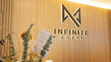 Pared de madera con el logotipo del Hotel Infinity y un cartel con información.