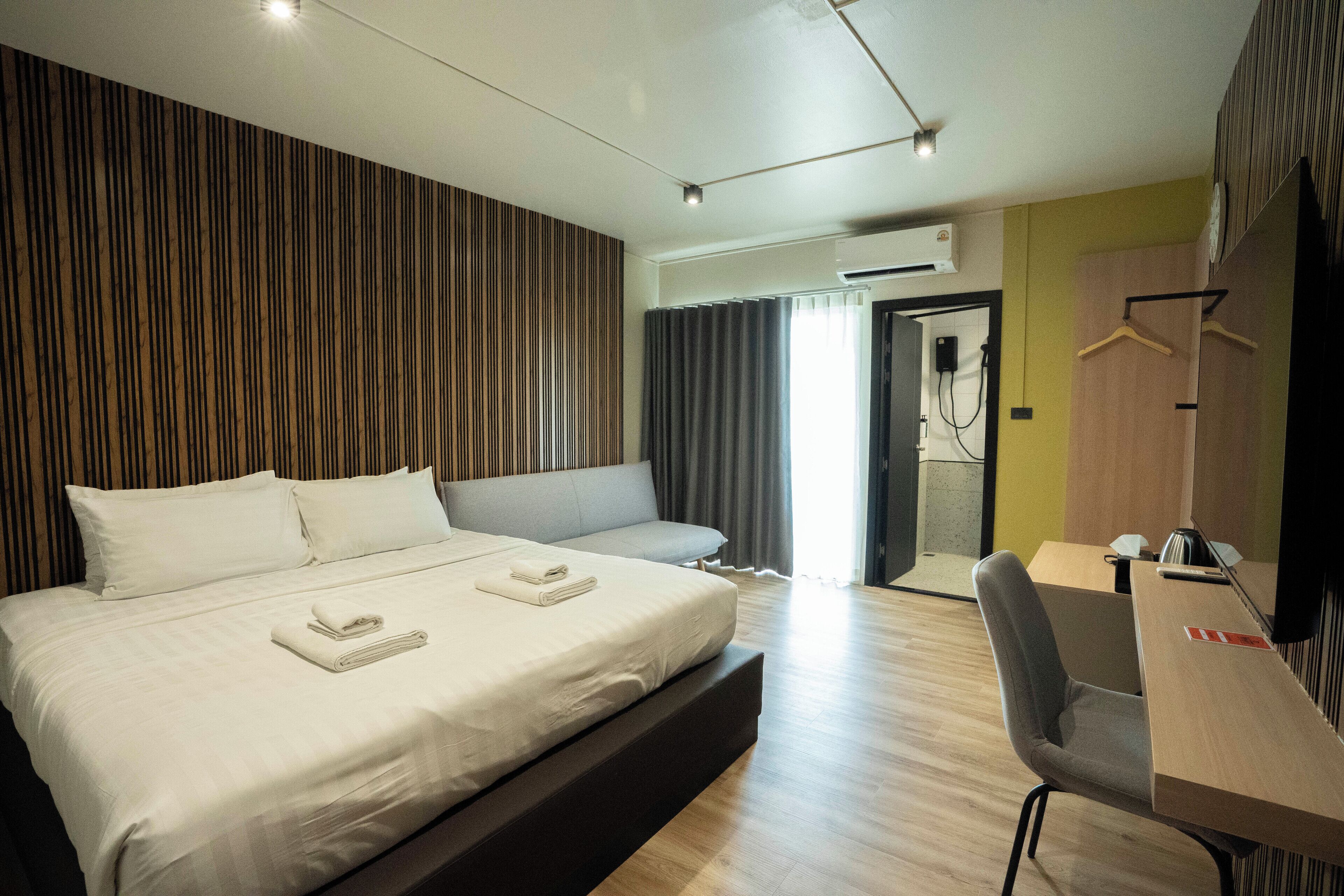 Una camera d'albergo moderna con un grande letto, una scrivania e un angolo salotto.
