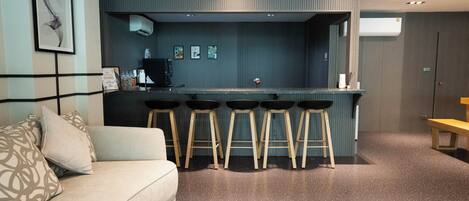 Una sala de estar moderna con un sofá, una zona de bar con taburetes y un banco.