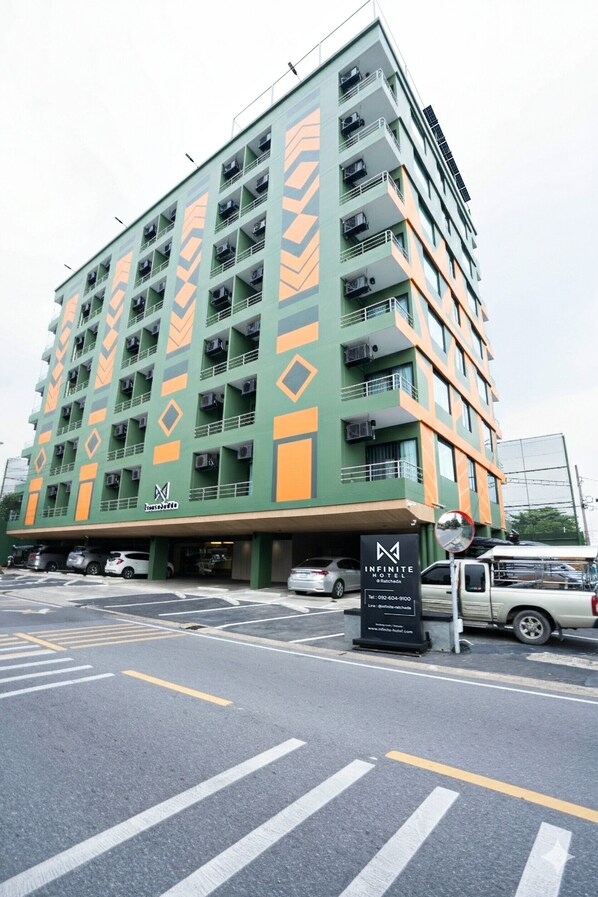 A multi-story hotel with a distinctive geometric facade, multiple balconies, and a sign indicating it is the Infinite Hotel. - Infinite Hotel at Ratchada (Bangkok)