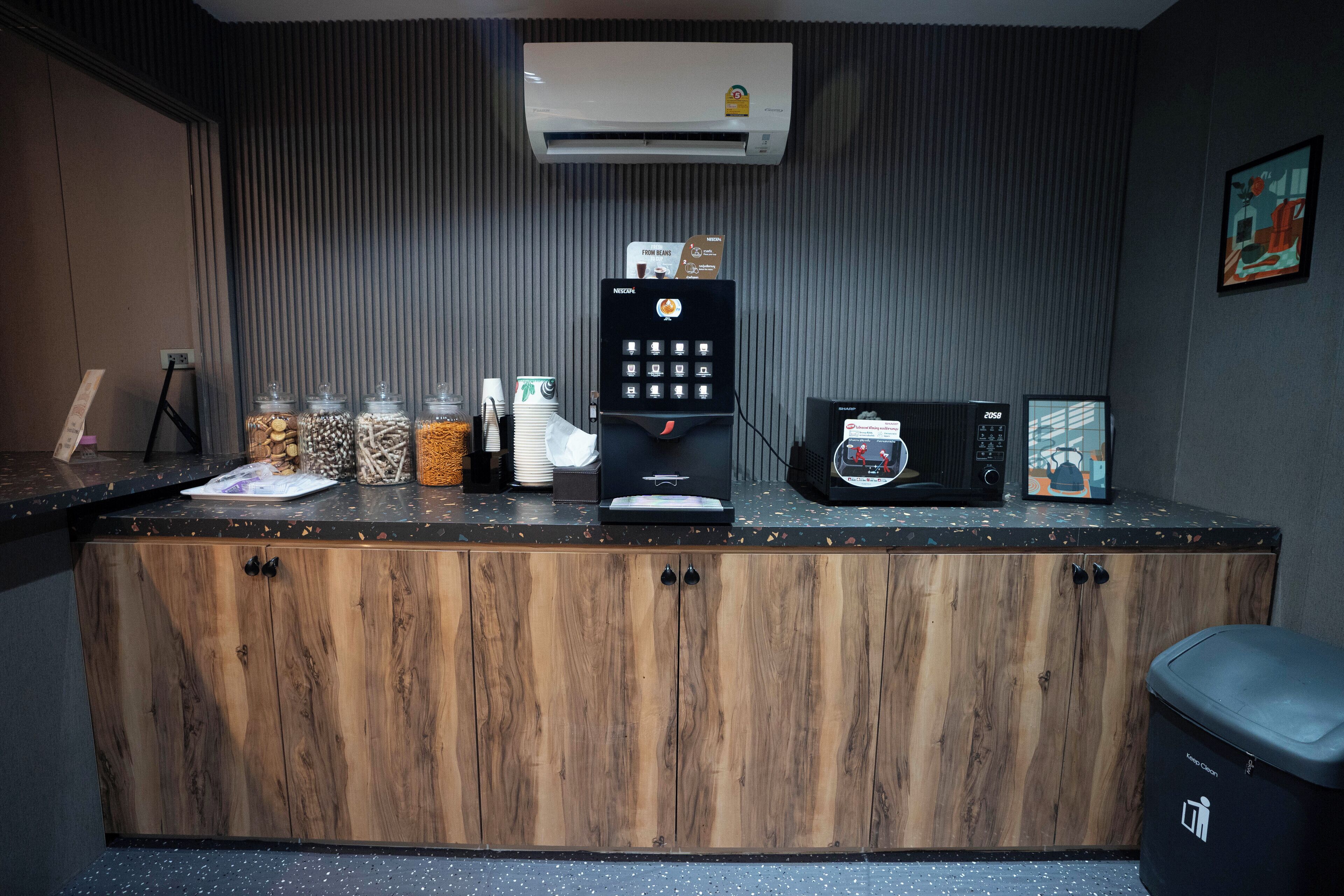 Uma bancada de cozinha com máquina de café, micro-ondas e potes com ingredientes.