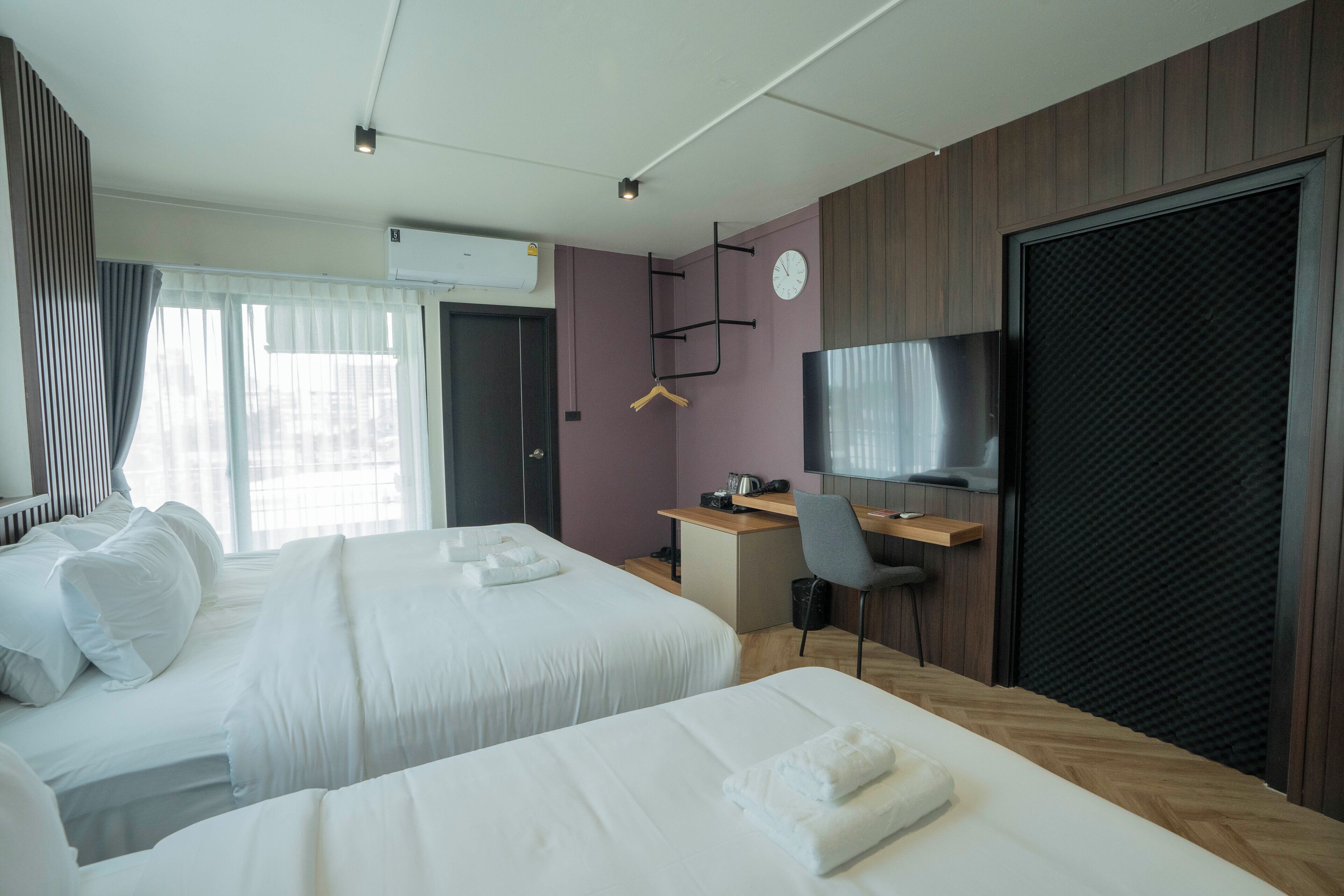 A hotel room with two beds, a desk, a chair, a television, and a wardrobe.