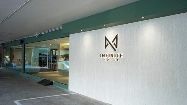 En modern hotellentrél med en minimalistisk design, med en framträdande logotyp och en glasfasad.