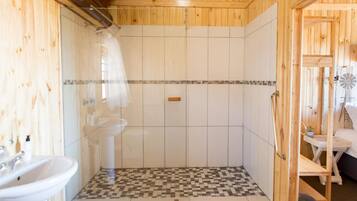 Un bagno con doccia, lavandino e pavimento a scacchi.