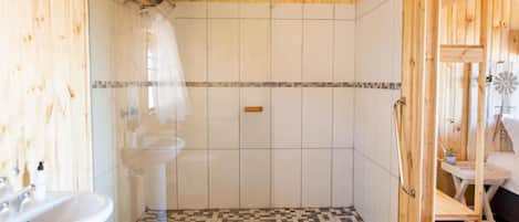 A bathroom with a shower, a sink, and a checkered floor.