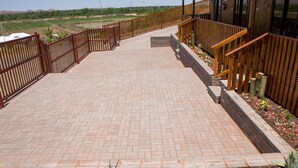 A paved pathway leading to a wooden building with a staircase. - Kalahari Lion's Rest (Upington)