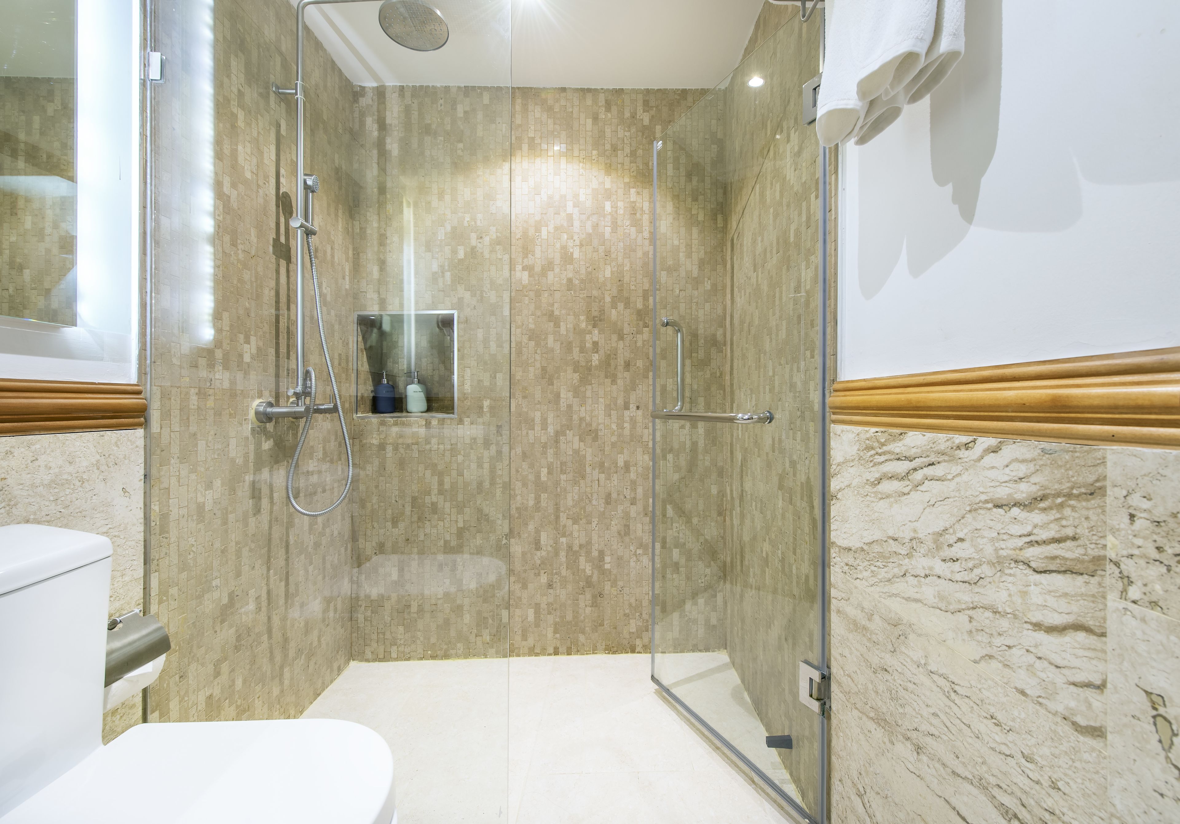 A modern bathroom with a glass-enclosed shower, a toilet, and a sink.