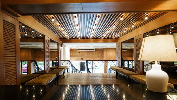 A spacious lobby with wooden flooring, benches, and a modern ceiling design with recessed lighting. - THE Posh Phayathai (Bangkok)
