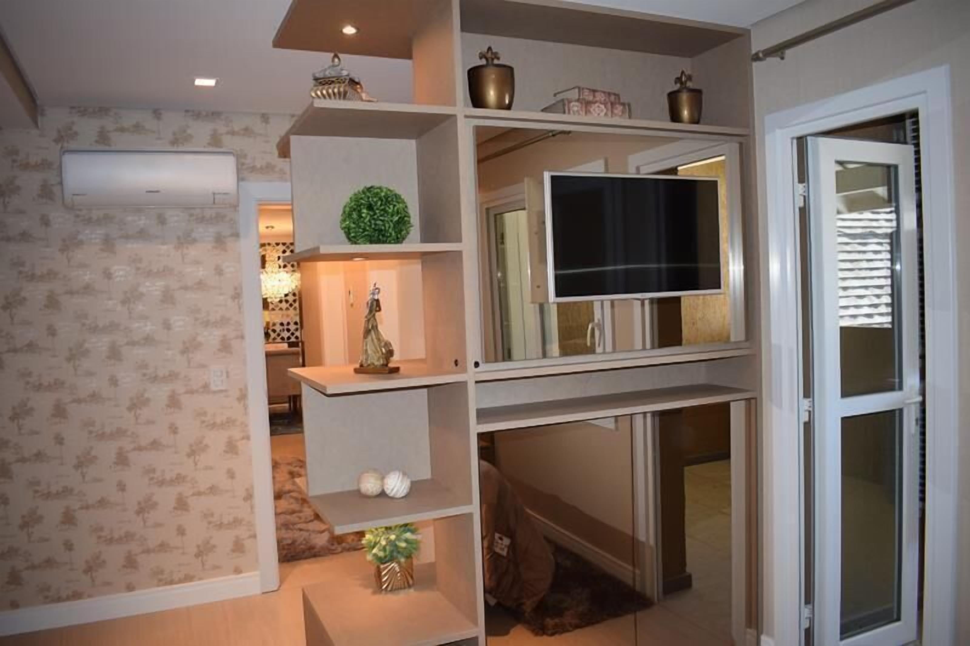 A living room with a TV on a shelf, a fireplace, and a door with blinds.