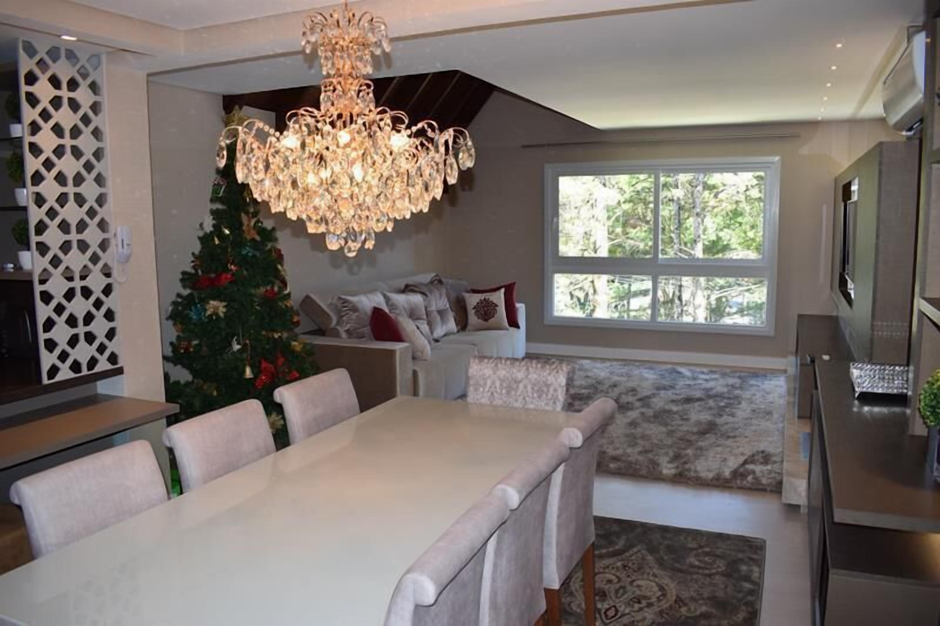 A modern kitchen with a dining area, a chandelier, a Christmas tree, and a large window.
