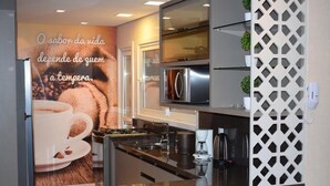 Une cuisine moderne dotée d’appareils électroménagers en acier inoxydable, d’une machine à café et d’un mur décoratif orné d’une affiche sur le thème du café.