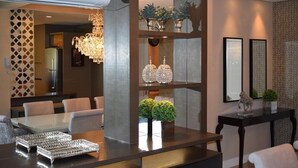 Un hall d’hôtel moderne avec un espace salon central, des éléments décoratifs en verre et un lustre.