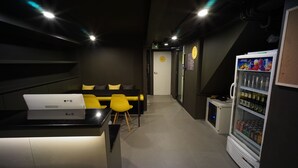 A modern room with a desk, yellow chairs, a refrigerator, and a microwave. - BRB Hostel Bangkok Silom (Bangkok)
