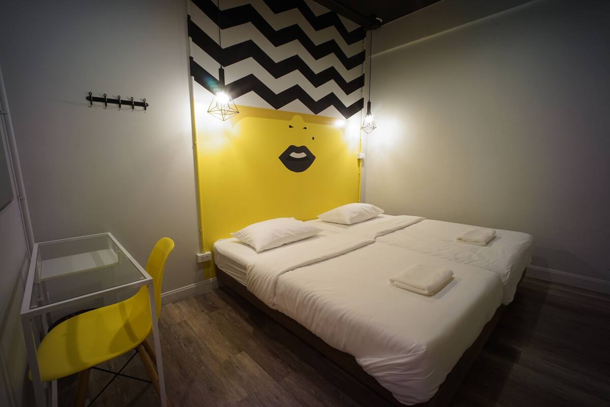 Een kamer met een bed, een klein tafeltje en een stoel.