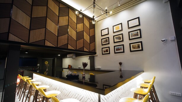 A modern kitchen with a central island, bar stools, and framed pictures on the wall. - BRB Hostel Bangkok Silom (Bangkok)