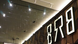 A modern interior with a geometric wall design, a yellow sofa, and a wooden table. - BRB Hostel Bangkok Silom (Bangkok)