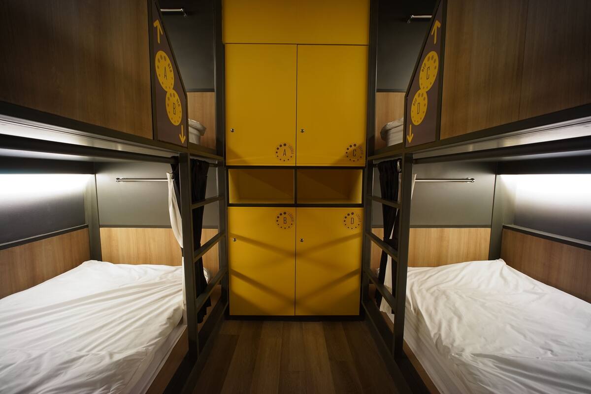 Een treincoupé met twee slaapplaatsen, houten wandbekleding en een gele wand in het midden met aanduidingen van de compartimenten.