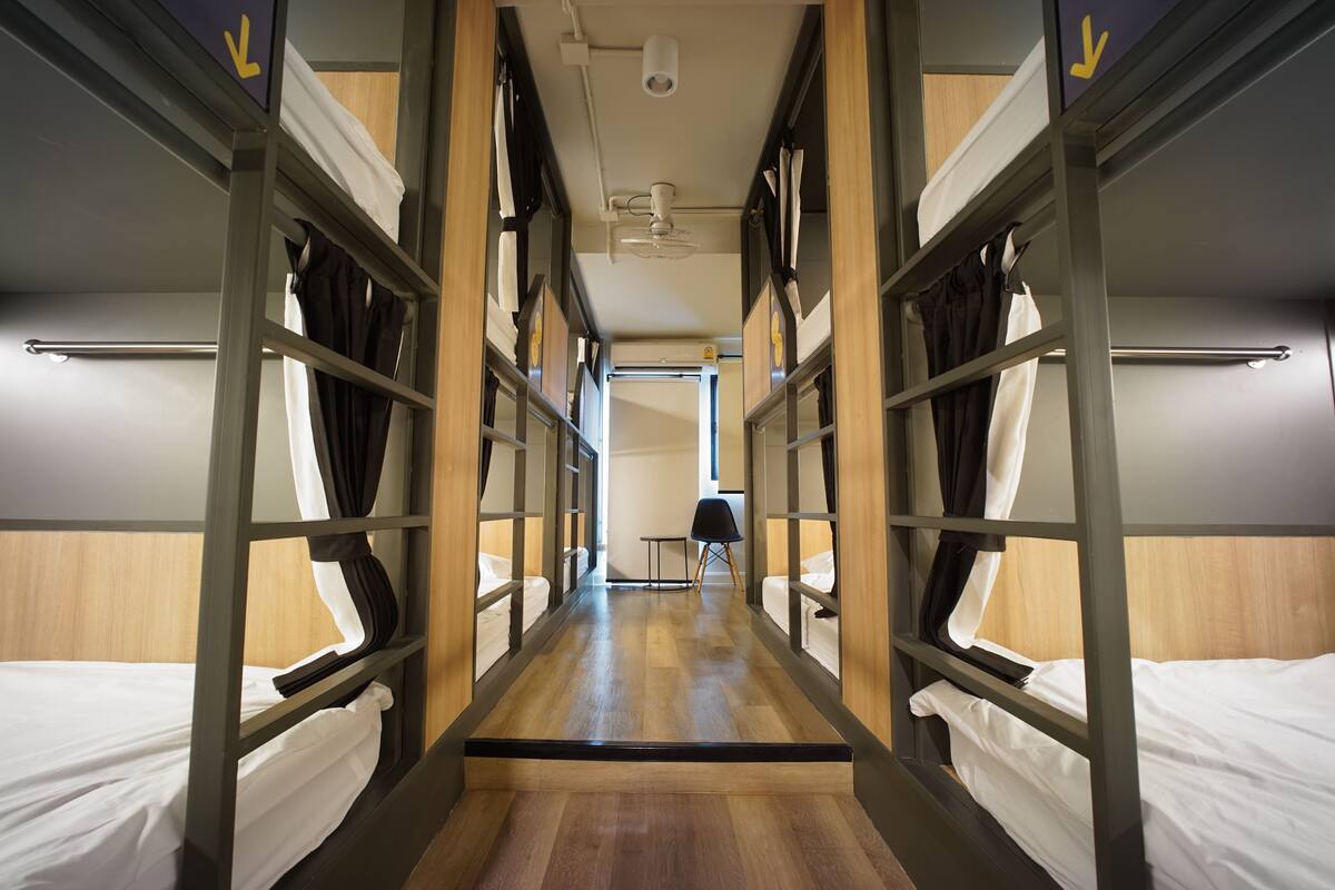 Een gang met stapelbedden, een plafondventilator en een deur naar een andere kamer.