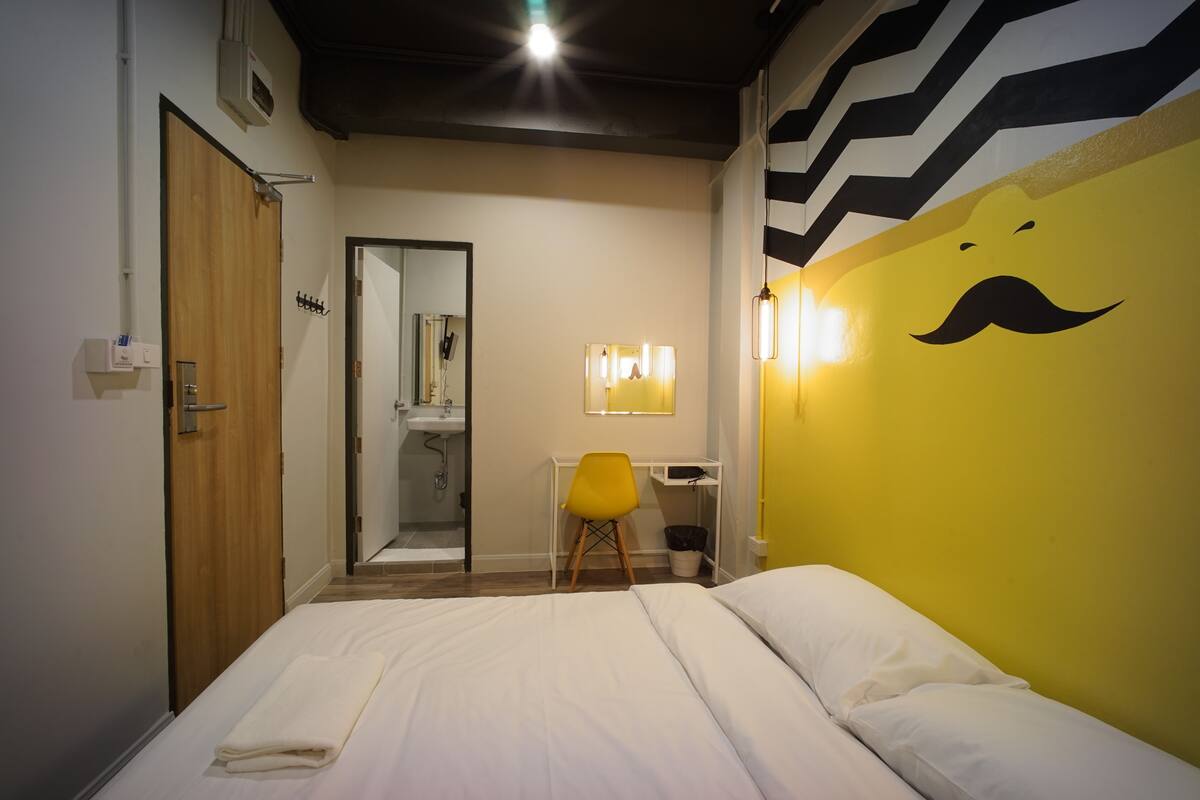 Een hotelkamer met een bed, een bureau, een stoel, een spiegel en een muur met een snorrelijf.