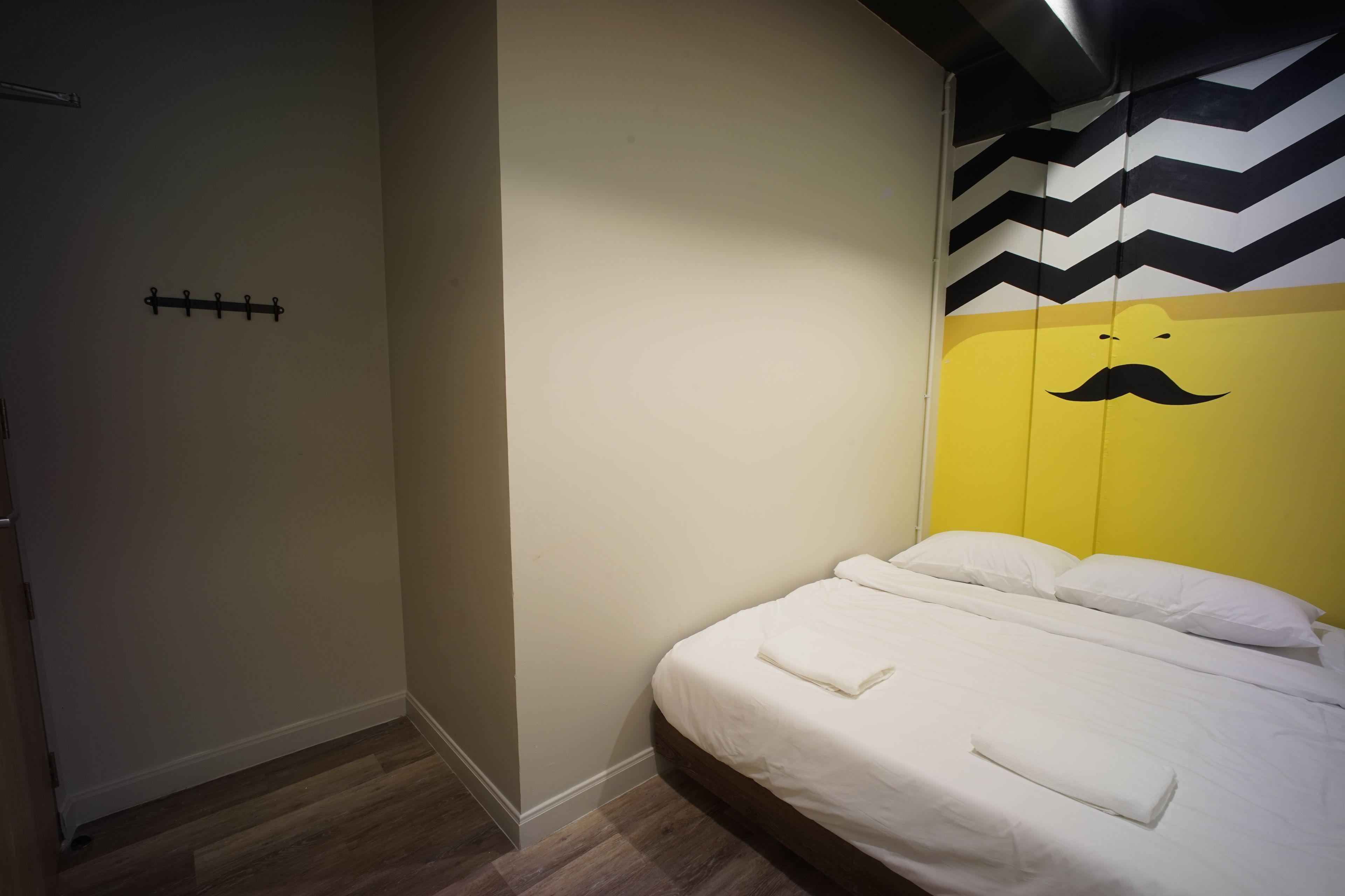A bedroom with a bed, a wall-mounted coat rack, and a chevron-patterned ceiling.