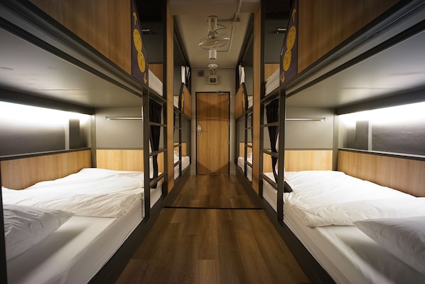 A train compartment with wooden paneling, metal beds, and overhead lighting. - BRB Hostel Bangkok Silom (Bangkok)