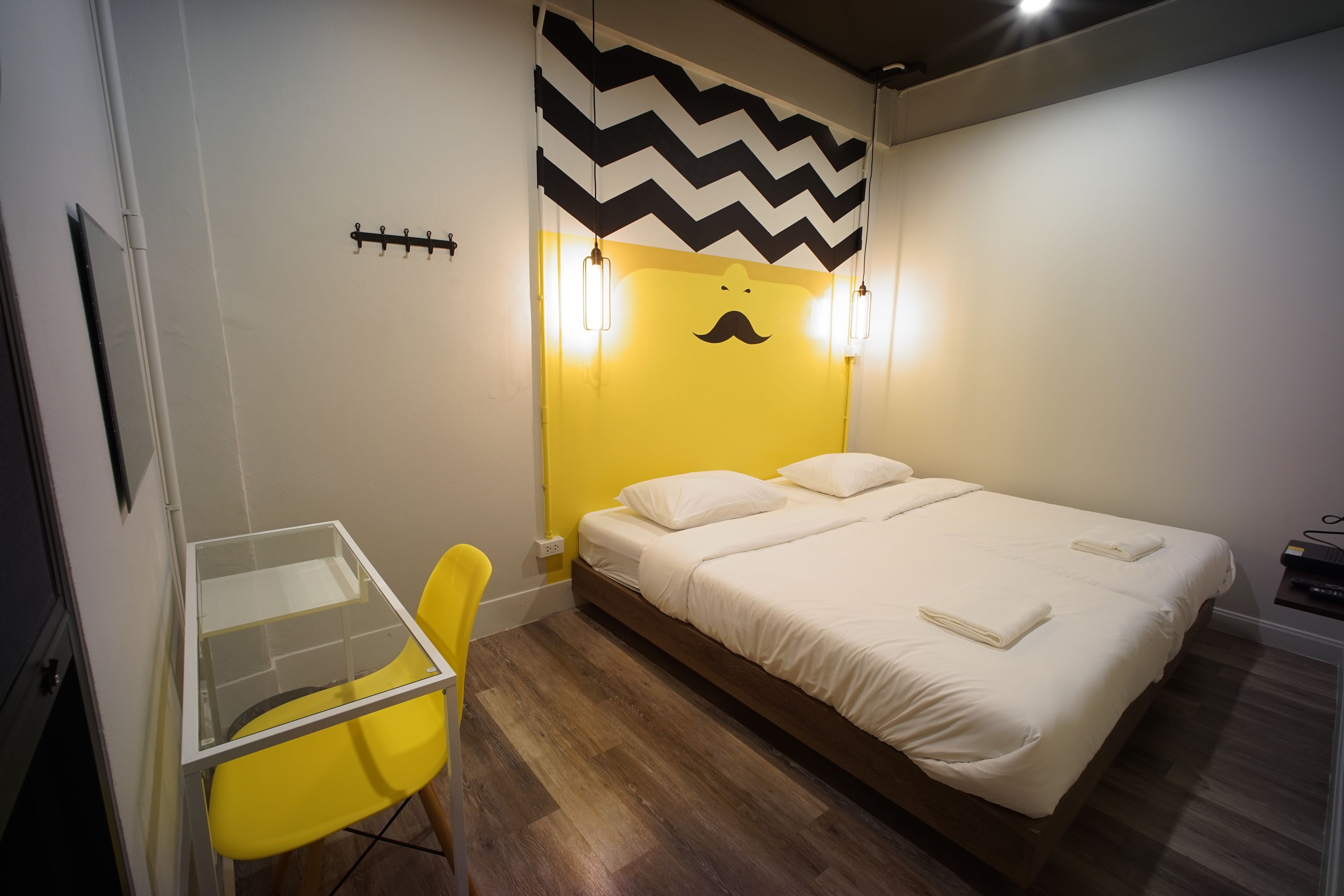 Una camera d'albergo con un letto, una sedia, una scrivania e una parete con motivo a zig-zag.
