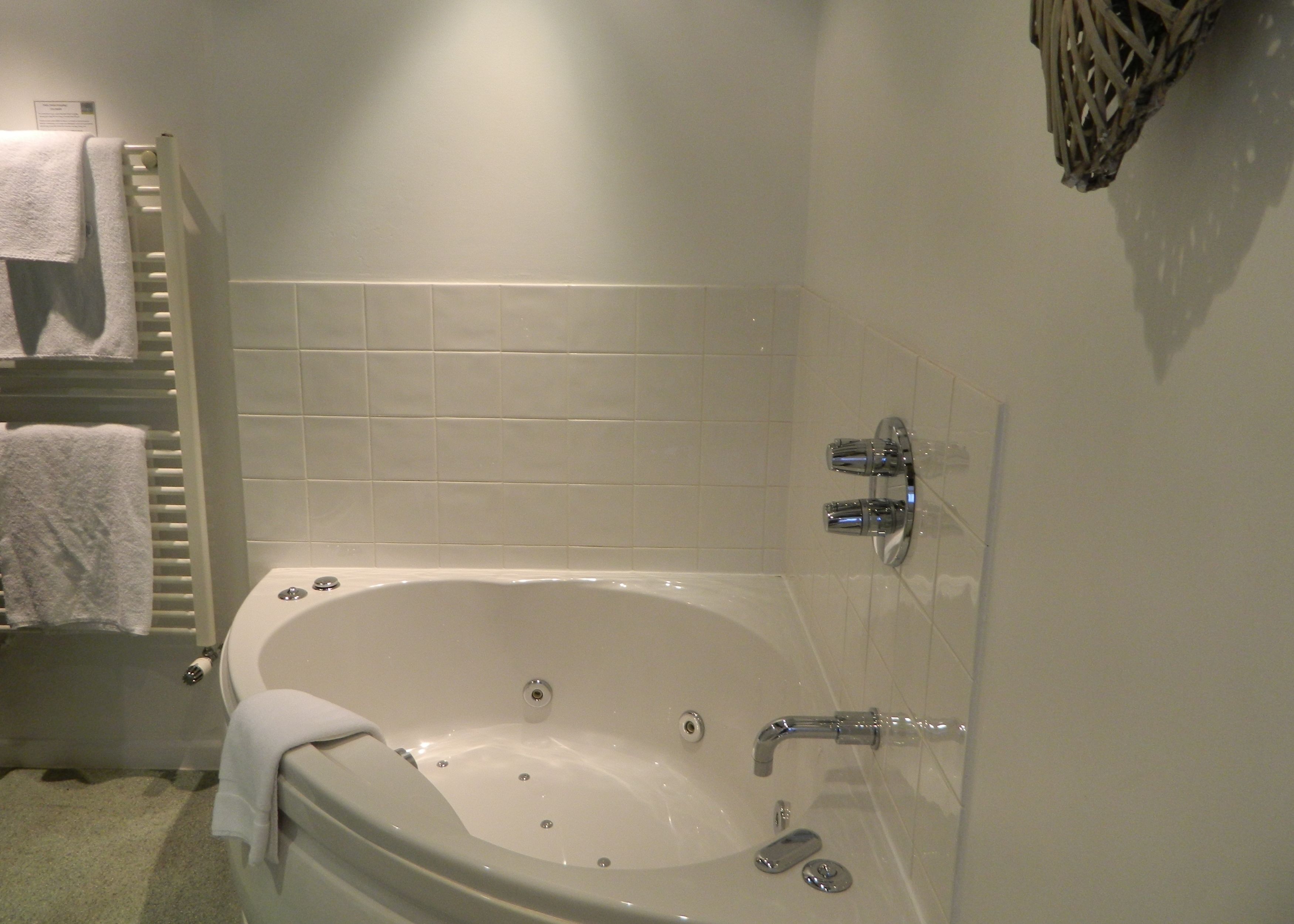A bathroom with a bathtub, white tiles, a towel rack, and a showerhead.