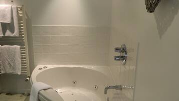 A bathroom with a bathtub, white tiles, a towel rack, and a showerhead.