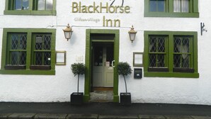 Un edificio con un letrero que dice "The Black Horse Inn" y una puerta verde.