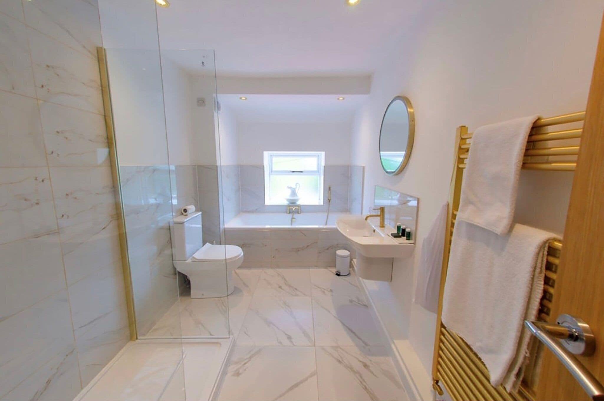 A modern bathroom with a glass shower enclosure, a bathtub, a toilet, and a sink with a mirror.