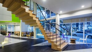 Un interno moderno con una scala in legno, zone relax e ampie finestre con vista sulla strada.