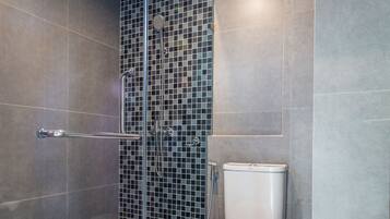 A modern bathroom with a glass-enclosed shower, a toilet, and a tiled floor.